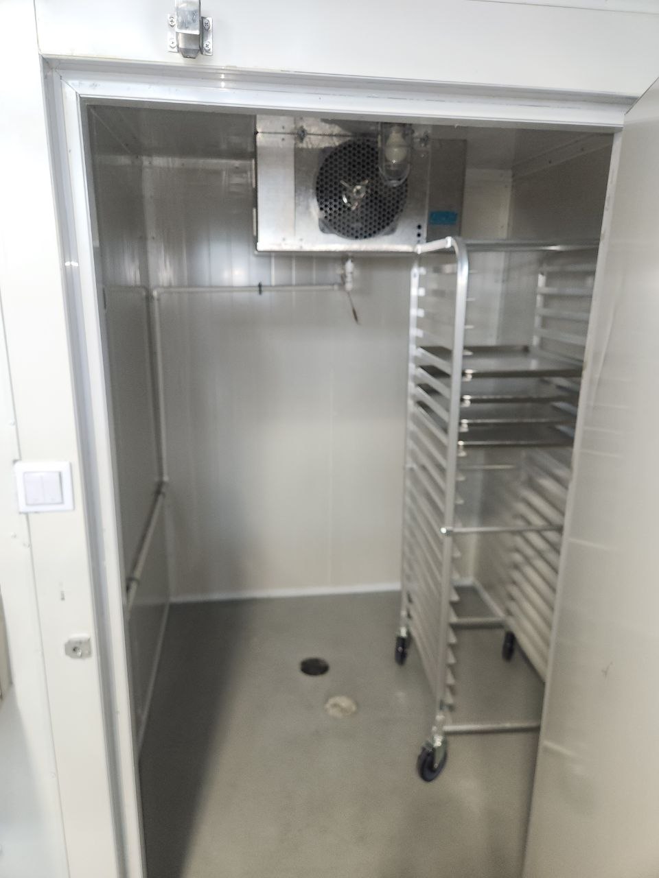 Cold storage room with an evaporator unit, rolling baking rack and floor drain